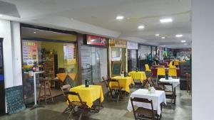 a restaurant with tables and chairs and yellow tables at FLAT Jardim de Alah - Frente Praia in Salvador