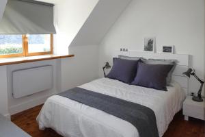 ein Schlafzimmer mit einem Bett mit lila Kissen und einem Fenster in der Unterkunft Holiday Home Locquirec - BRE05104e-F in Locquirec