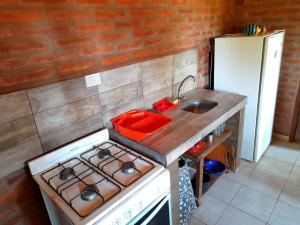 uma pequena cozinha com um fogão e um lavatório em Cabaña EL ZORZAL de Villa del Dique em Villa del Dique