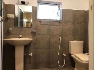 a bathroom with a toilet and a sink and a window at Wilpattu Wildhideaway Lodge in Galkadawala