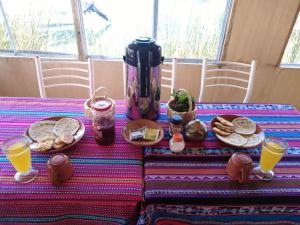 Uros Suyawi Titicaca Lodge في بونو: طاولة مع وجبة إفطار من الخبز وعصير البرتقال