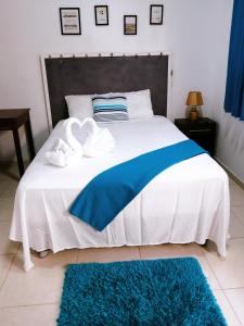 a bed with a blue and white blanket and two towels at Vista Palmeras in Zorritos
