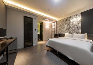 una camera con letto, scrivania e TV di West In Hotel Yeosu a Yeosu