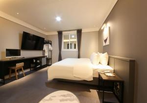 una camera d'albergo con letto, scrivania e TV di West In Hotel Yeosu a Yeosu