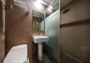 West In Hotel Yeosu في يوسو: حمام مع حوض ومرحاض ومرآة