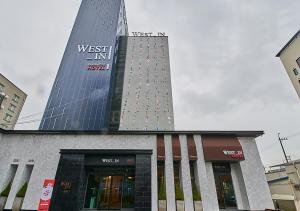 丽水市West In Hotel Yeosu的一座高楼，楼顶有标志