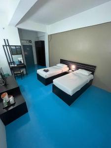 Habitación de hotel con 2 camas y suelo azul en Kuala Melaka Inn en Pantai Cenang