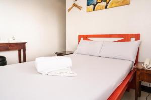 um quarto com uma cama branca e uma cabeceira em madeira em GETZ HOTEL MANILA em Manila