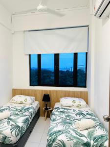 two beds in a room with a large window at Imperio Homestay Alor Star in Alor Setar