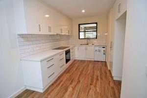 a kitchen with white cabinets and a wooden floor at Old Port Townhouse Central to Everything in Echuca