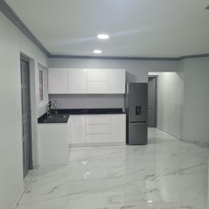 an empty kitchen with white cabinets and a refrigerator at New Modern Apartment in Willemstad