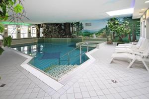 a large swimming pool with white chairs in a building at Cottages in fir park, fir in Tanne