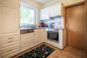 a kitchen with white cabinets and a kitchen rug at Cottage by the meadow, fir in Tanne