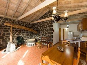 sala de estar con mesa de madera y pared de piedra en Holiday house, Praínha de Baixo, Pico, Azores, en Santa Luzia