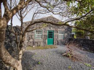 een stenen huis met een groene deur en een stenen muur bij Holiday house, Praínha de Baixo, Pico, Azores in Santa Luzia