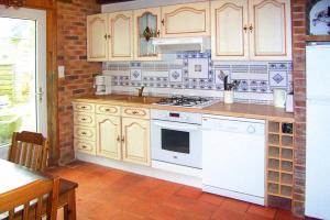 a kitchen with white appliances and a brick wall at Granite stone house with fireplace, Plouguerneau in Plouguerneau