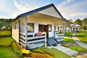 a tiny house with a porch and a yellow chair at Holiday resort, Jaroslawiec in Jarosławiec