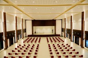 un pasillo vacío con sillas rojas y un escenario en ARK HOTEL AND CONVENTION CENTRE, en Mundūr