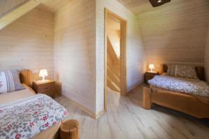 two beds in a room with wooden walls and two lamps at Holiday resort, Wicie in Wicie