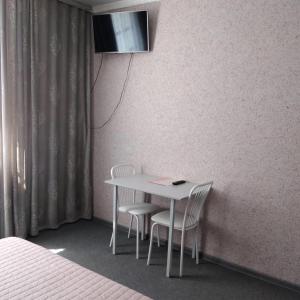 a table with two chairs and a television on a wall at Guest House on Partizanskaya in Barnaul