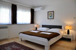 a bedroom with a bed with two lamps and two windows at Apartments Crobeg in Rab