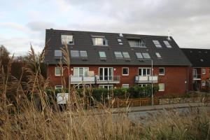 un edificio de ladrillo rojo con techo negro en Ferienwohnung, St Peter - Ording, en Sankt Peter-Ording