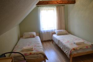 two beds in a small room with a window at Spēlmaņu krogs in Alsunga