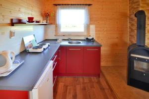a kitchen with red cabinets and a sink and a stove at Comfortable bungalows with a fireplace and terrace Jaroslawiec in Jarosławiec