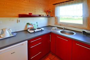 a kitchen with red cabinets and a sink and a window at Comfortable bungalows with a fireplace and terrace Jaroslawiec in Jarosławiec