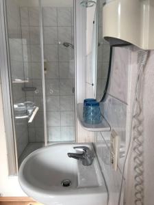 a white bathroom with a sink and a shower at Sporthostel Rössle in Schluchsee