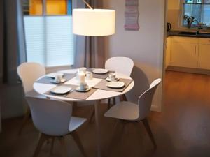 een witte tafel met witte stoelen en een lamp bij Home port holiday home, Dornum in Dornumersiel