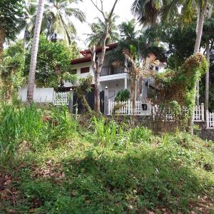 Brown Birds Villa في تانجالي: منزل به سياج أبيض وأشجار نخيل