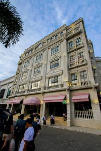 The Plaza Hotel Balanga City في Balanga: مبنى كبير فيه ناس واقفه خارجه