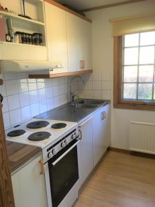 uma cozinha com um fogão e um lavatório em Idyllic bungalow close to sea and forest em Ronneby