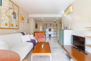 a living room with a white couch and a tv at Benalmadena with seasonal pool & parking near the beach in Arroyo de la Miel