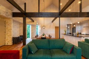 a living room with a green couch and a kitchen at Kitsune House by H2 Life in Niseko