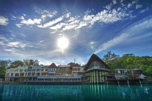 a building on the water with the sun in the sky at Ramada by Wyndham Langkawi Marina in Kuah