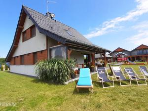 un groupe de chaises posées sur l'herbe devant une maison dans l'établissement Holiday Home in Mielno near Beach & Lake, à Mielenko