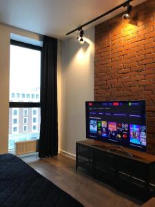 ウファにあるKEY апарт-отельのレンガの壁に大画面薄型テレビが備わるベッドルーム1室が備わります。