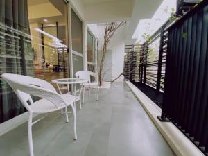 einen Balkon mit weißen Stühlen und einem Tisch darauf in der Unterkunft 遊虎尾 in Huwei