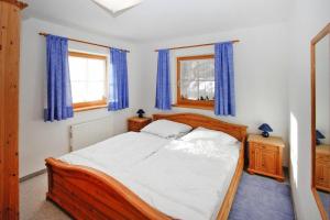1 dormitorio con cama de madera y cortinas azules en Chalet, Königsleiten, en Königsleiten