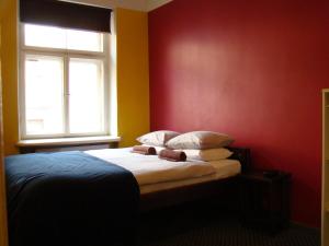 a bedroom with a bed with red walls and a window at Naughty Squirrel Backpackers Hostel in Rīga