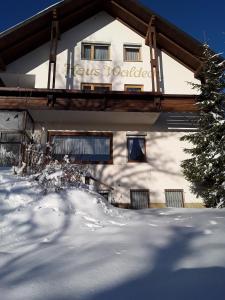 a building with a sign on it in the snow at Pension Waldeck Fleckl in Warmensteinach