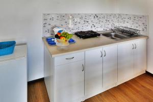 a white kitchen with a sink and a counter at Holiday bungalow for 4 people Jaroslawiec in Jarosławiec