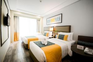 um quarto de hotel com duas camas com um cão sentado na cama em Belmont Hotel Boracay em Boracay