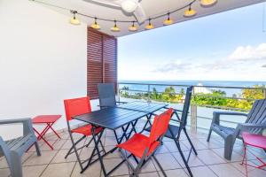 een eettafel en stoelen op een balkon met uitzicht op de oceaan bij Océanides - studio rénové avec magnifique vue mer - Saint-Gilles-Les-Bains in Saint-Gilles-les-Bains