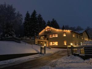 a house with lights on it in the snow at Pension Pöhlbergblick Annaberg in Annaberg-Buchholz