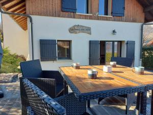 Une table et des chaises en bois sont disponibles sur la terrasse. dans l'établissement Entre lac et montagne, chaleureuse maison 3 pièces avec très belle vue lac d'Annecy. Terrasse, jardin, parking, cheminée, barbecue …., à Saint-Jorioz