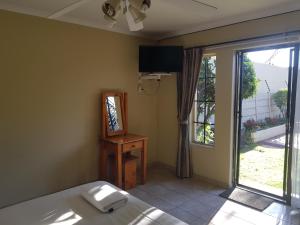 a bedroom with a bed and a mirror and a window at Louhallas Accommodation in Edenvale