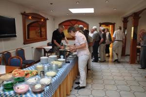 Eine Frau steht vor einem Tisch mit Essen in der Unterkunft Hotel Sassor in Battenberg